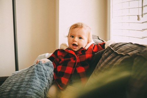 baby smiling in a plaid sweater on a couch in Napa Ca